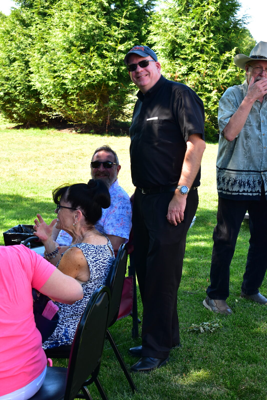 Priest and guests smiling together on the lawn at the BBQ