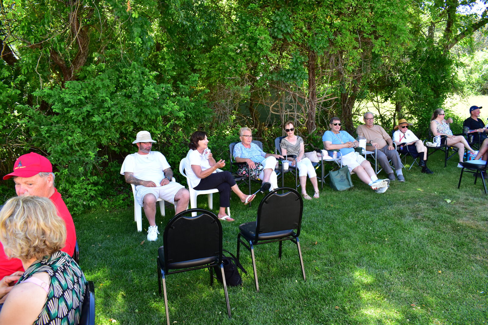 Guests seated in lawn chairs along the tree line during the BBQ
