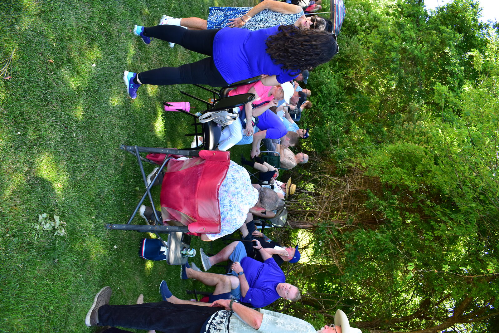 Parish community relaxing in folding chairs under the trees during the BBQ