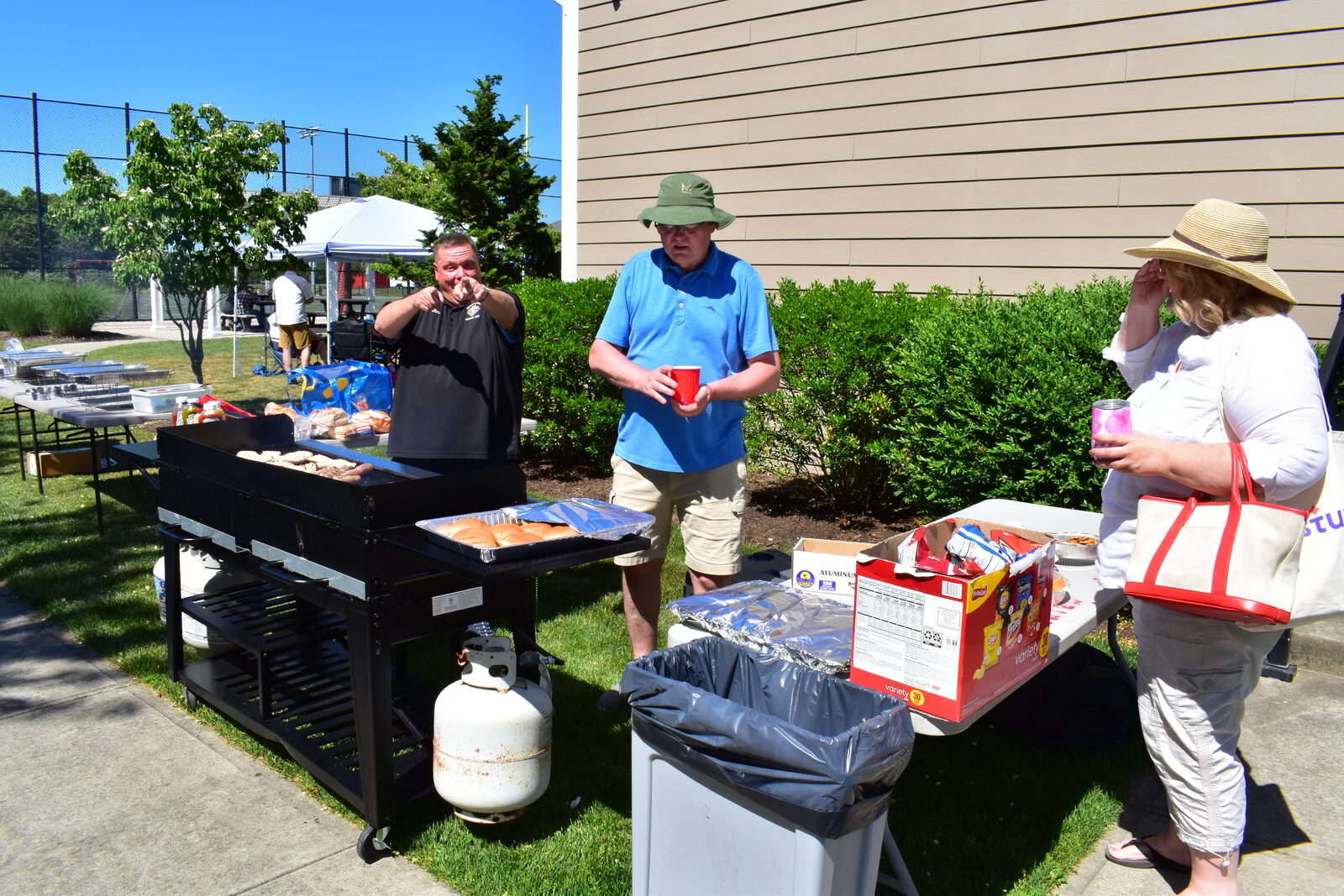 Cook at the griddle with guests nearby during the outdoor BBQ