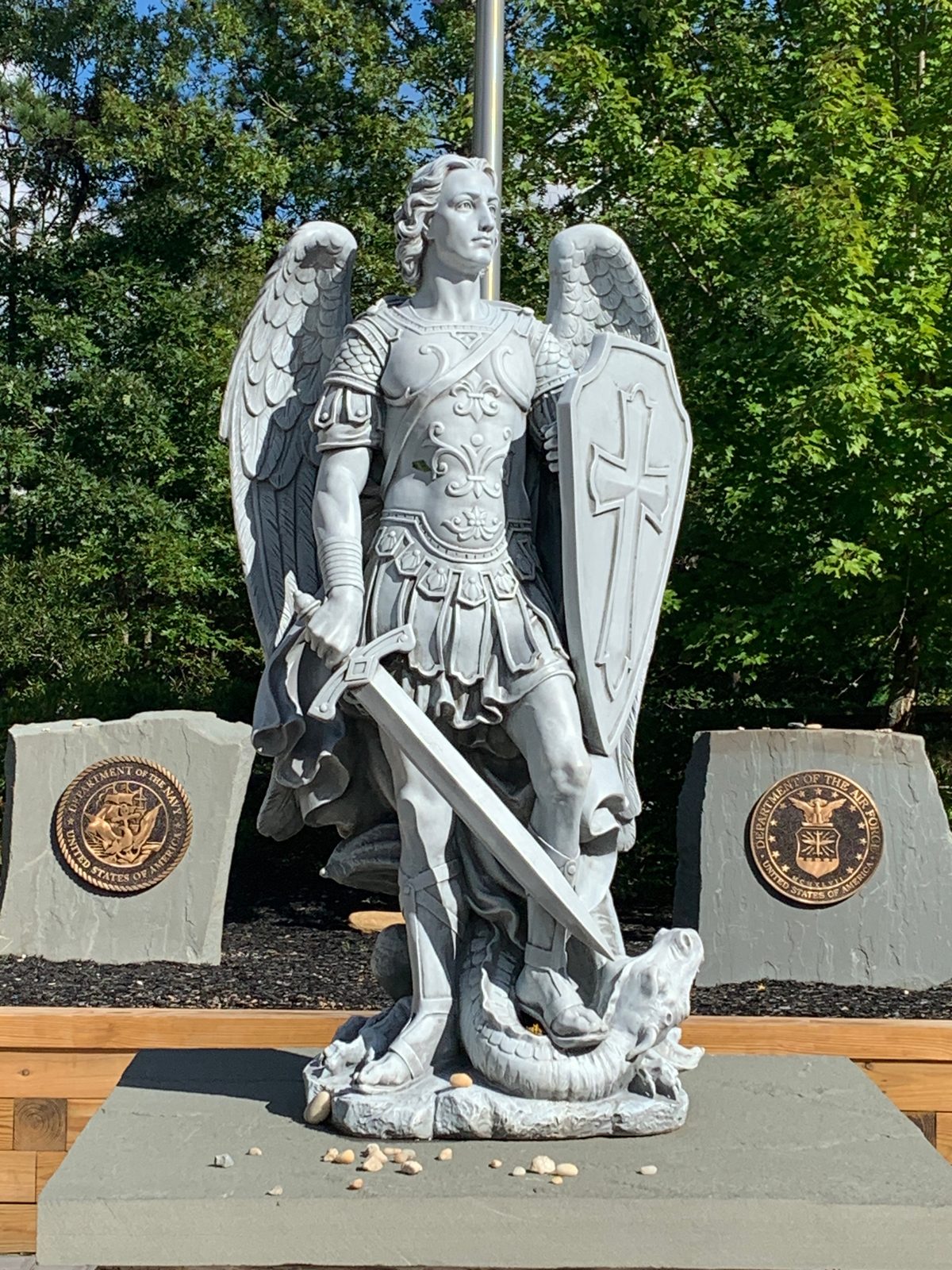 Close view of the St. Michael the Archangel statue with Navy and Air Force emblems behind
